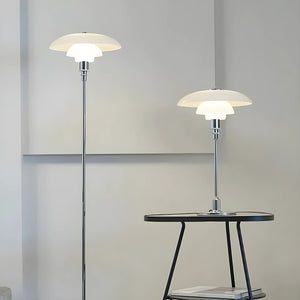 Modern floor and table lamps with tiered, saucer-shaped white shades and sleek metal stems.