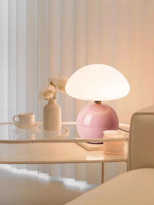 Pink-based table lamp with a round white shade.