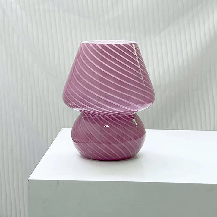 Pink glass table lamp with spiral pattern.