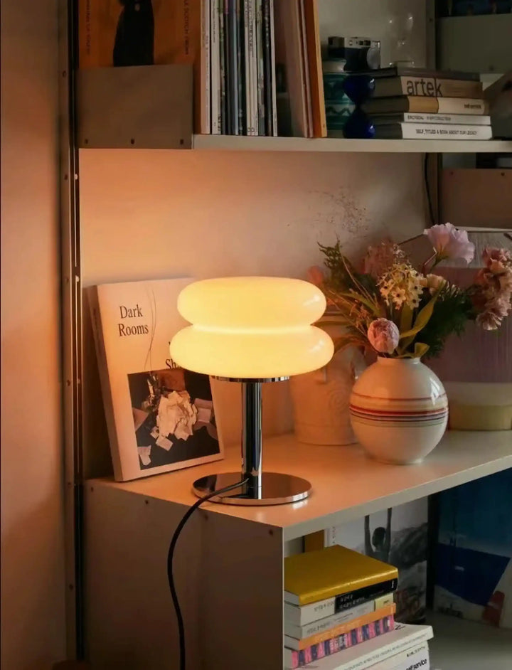 Table lamp with a round, pleated fabric shade emitting a warm glow.