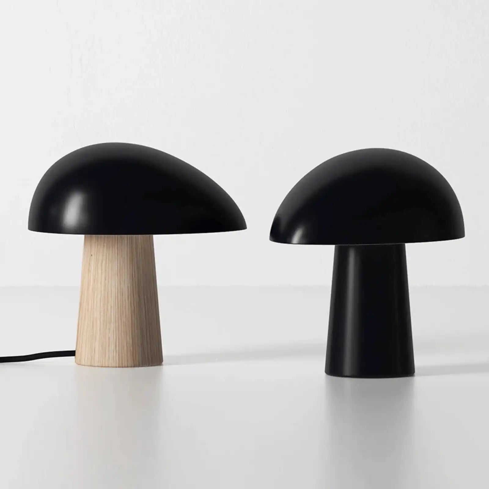 Two mushroom-shaped table lamps with rounded black tops and cylindrical bases.